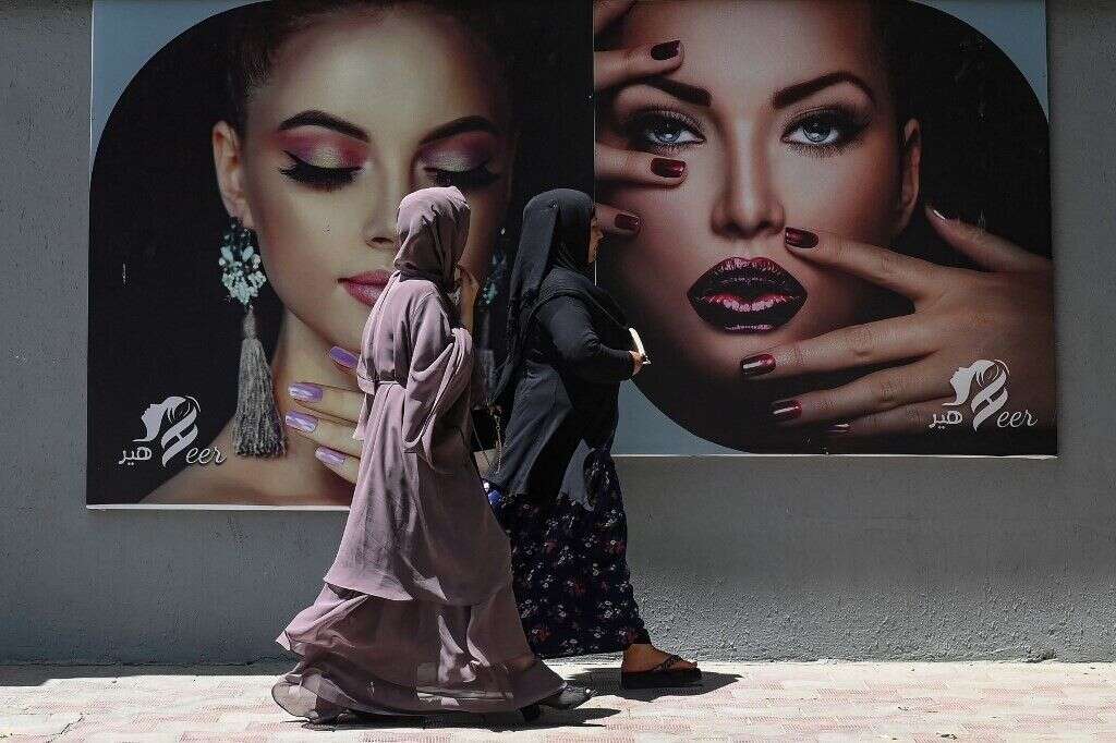 A Kaboul, des femmes en burqa devant un salon de beauté, le 7 août.