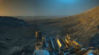 Le rover Curiosity Mars de la NASA a utilisé ses caméras de navigation en noir et blanc pour photographier cette scène ; la couleur bleue, orange et verte ont été ajoutées ensuite dans le cadre d'une interprétation artistique.