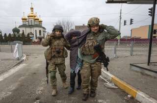 Des soldats ukrainiens aidant une femme âgée à Irpin, le 6 mars 2022.