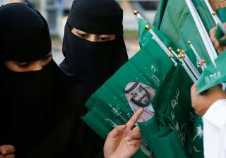Sur cette photo d'illustration prise le 23 septembre 2019, des Saoudiennes achètent des drapeaux à l'effigie du prince héritiers MBS pour commémorer la réunification du pays. (AP Photo/Amr Nabil)