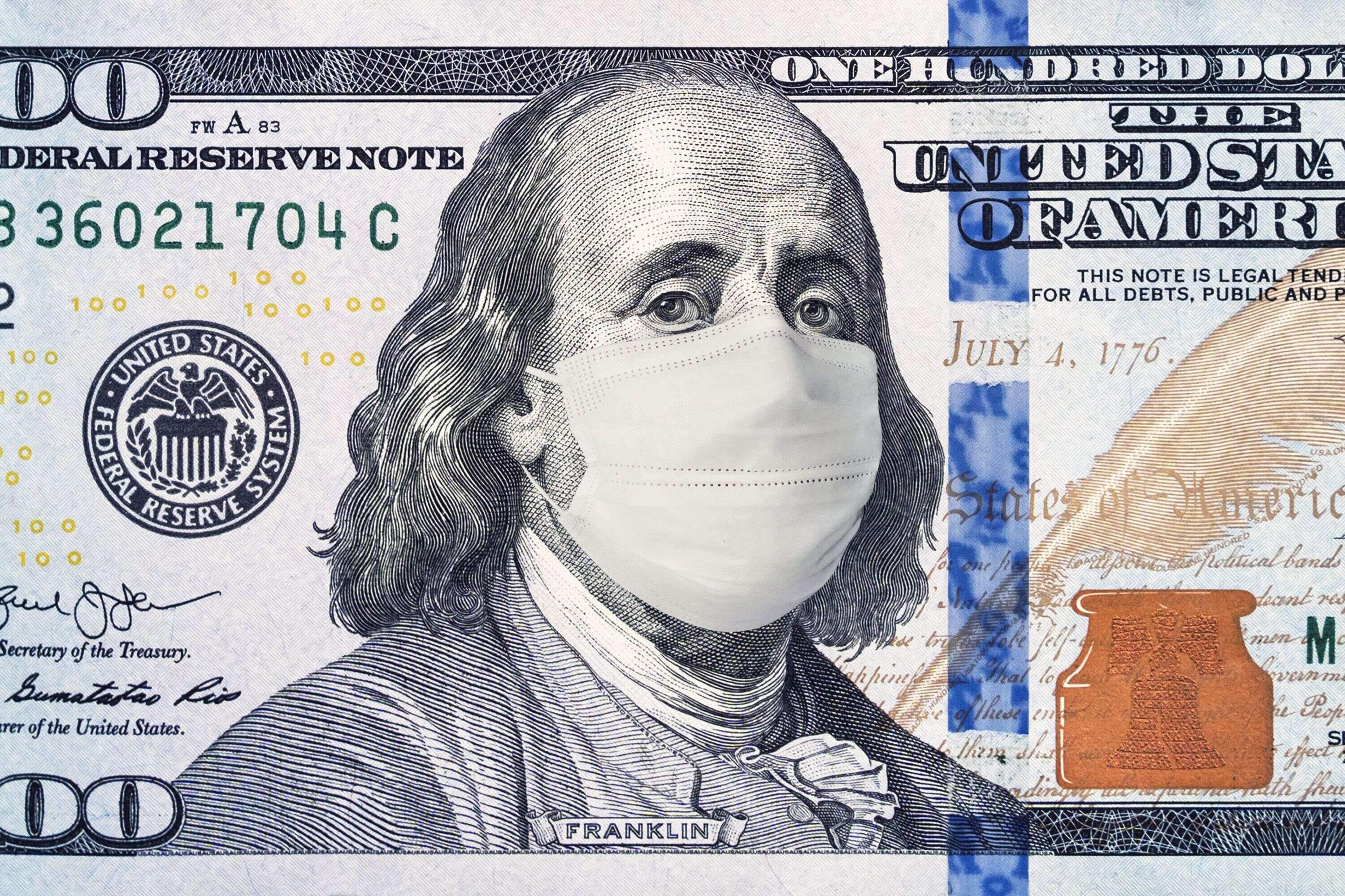 Symbole de la crise économique mondiale provoquée par le coronavirus: un billet de 100 dollars sur lequel l'effigie de Benjamin Franklin porte un masque anti COVID-19.