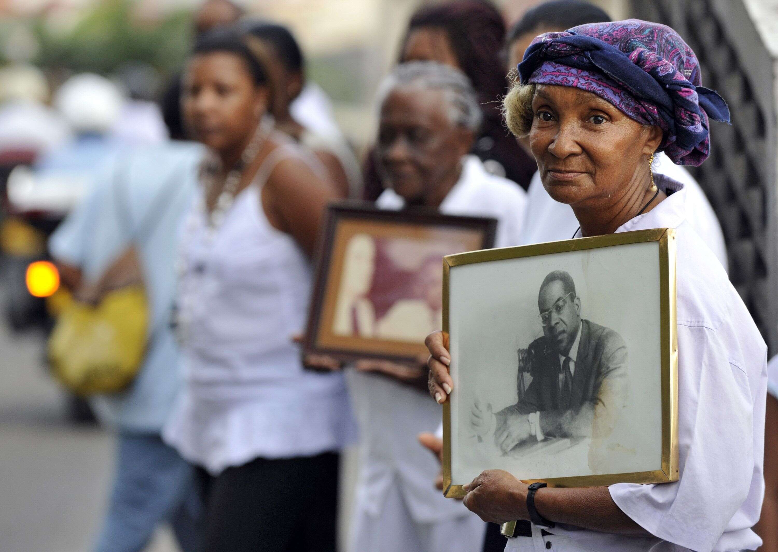 Une femme tient un portrait du poète français Aimé Césaire alors que le cercueil du poète est transporté dans les rues de Fort-de-France, le 18 avril 2008, sur l'île de la Martinique. Césaire a inventé le terme 