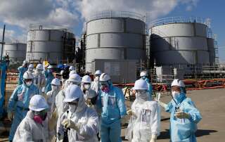 Des employés de TEPCO devant des citernes d'eau radioactive sur le site de Fukushima.