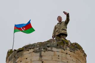 Un soldat azerbaïdjanais prend un selfie avec un drapeau national au sommet d'une tour à l'extérieur de la ville de Fuzuli le 26 novembre 2020. Le territoire doit être rendu à Bakou, comme le stipule l'accord de paix signé par l'Arménie et l'Azerbaïdjan le 9 novembre 2020. (Photo TOFIK BABAYEV/AFP via Getty Images)