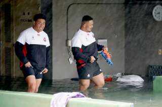 Les joueurs de l'équipe japonaise de rugby Takuya Kitade (à gauche) et Yusuke Kizu marchent dans allée inondée d'un stade de Tokyo après le passage du typhon Hagibis.