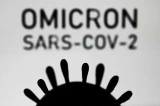 Coronavirus model and 'omicron sars-cov-2' sign displayed in the background are seen in this illustration photo taken in Krakow, Poland on November 28, 2021. (Photo by Jakub Porzycki/NurPhoto via Getty Images)