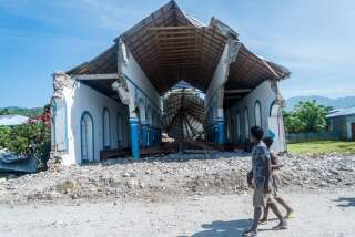 Deux Haïtiens passant devant une église détruite après le tremblement de terre (photo prise le 16 août 2021).