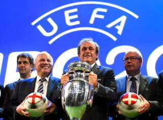 Michel Platini, ici photographié en 2014 aux côtés des patrons du football anglais (qui venaient alors d'obtenir l'organisation des phases finales de l'Euro 2020), est le grand architecte de cette édition singulière car répartie dans une dizaine de pays.