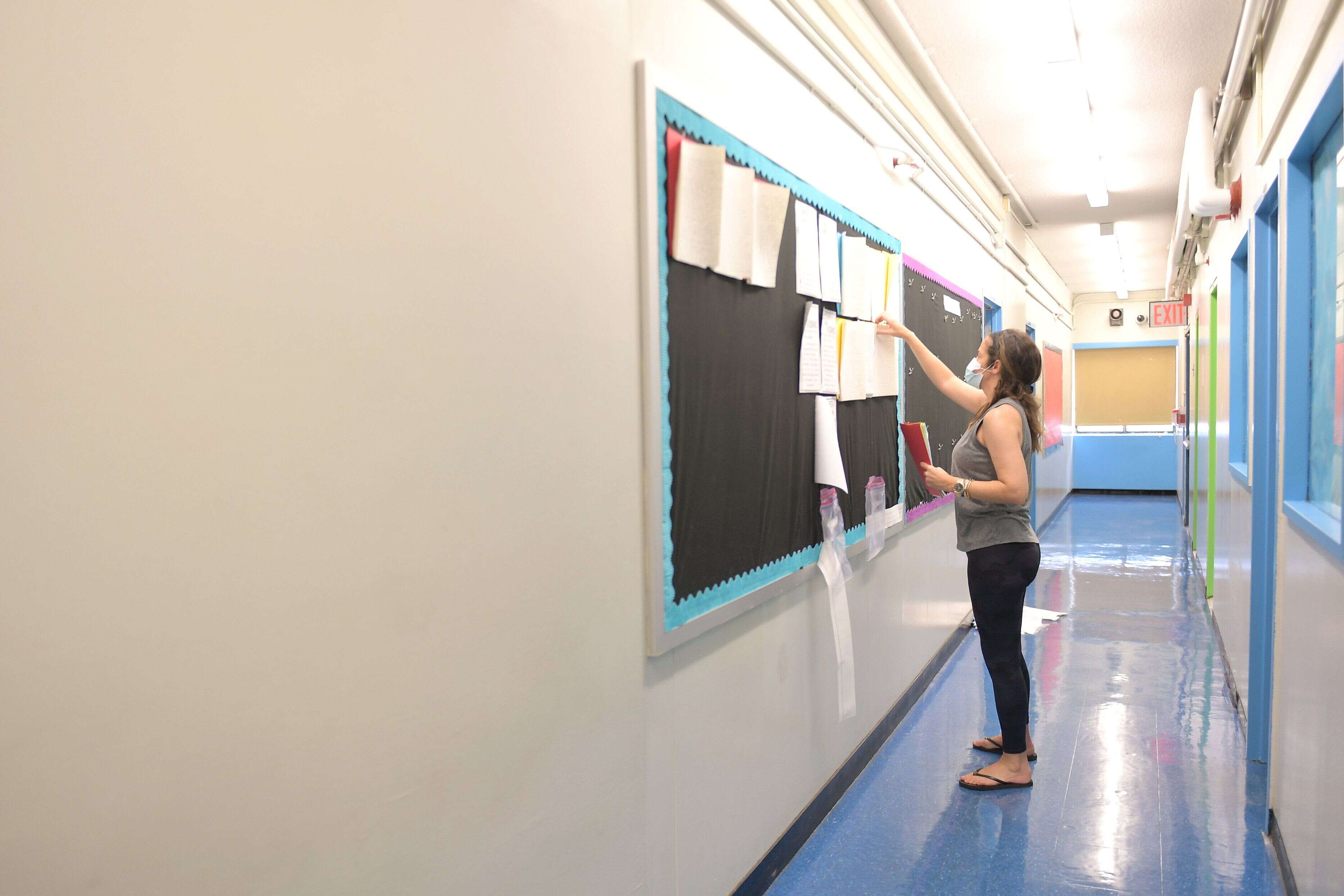 NEW YORK, NEW YORK - AUGUST 25: Teacher Marisa Wiezel, who is related to the photographer, removes student assignments which remained posted outside her classroom from the 2019/2020 school year at Yung Wing School P.S. 124 on August 25, 2020 in New York City. New York City public schools are scheduled to start September 10 with new guidelines in place for how they will operate.  (Photo by Michael Loccisano/Getty Images)