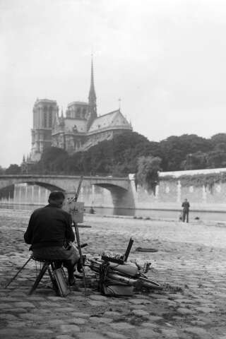 Un homme peint la cathédrale Notre-Dame depuis les quais de Seine en juillet 1945.