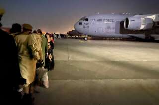 Des Afghans font la queue et montent à bord d'un avion militaire américain pour quitter l'Afghanistan, à l'aéroport militaire de Kaboul, le 19 août 2021, après la prise de contrôle militaire de l'Afghanistan par les Talibans. (Photo by SHAKIB RAHMANI/AFP via Getty Images)