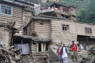 Des personnes face à des habitations endommagées suite aux crues dans la province du Nuristan province, en Afghanistan, le 31 juillet 2021.