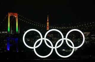 Les anneaux olympiques illuminés devant le Rainbow Bridge et la tour de Tokyo, le 1er décembre 2020, au Japon.