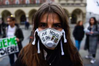 Une jeune fille proteste en portant un masque sur lequel est écrit 