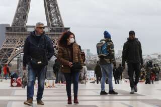 Des personnes devant la tour Eiffel à Paris, le 12 mars 2020.