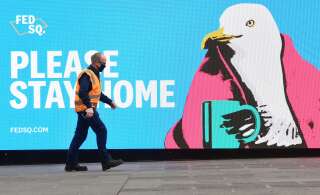 Un passant devant un panneau encourageant la population à rester chez soi à Melbourne le 28 mai, alors que la ville connaît un nouveau confinement.