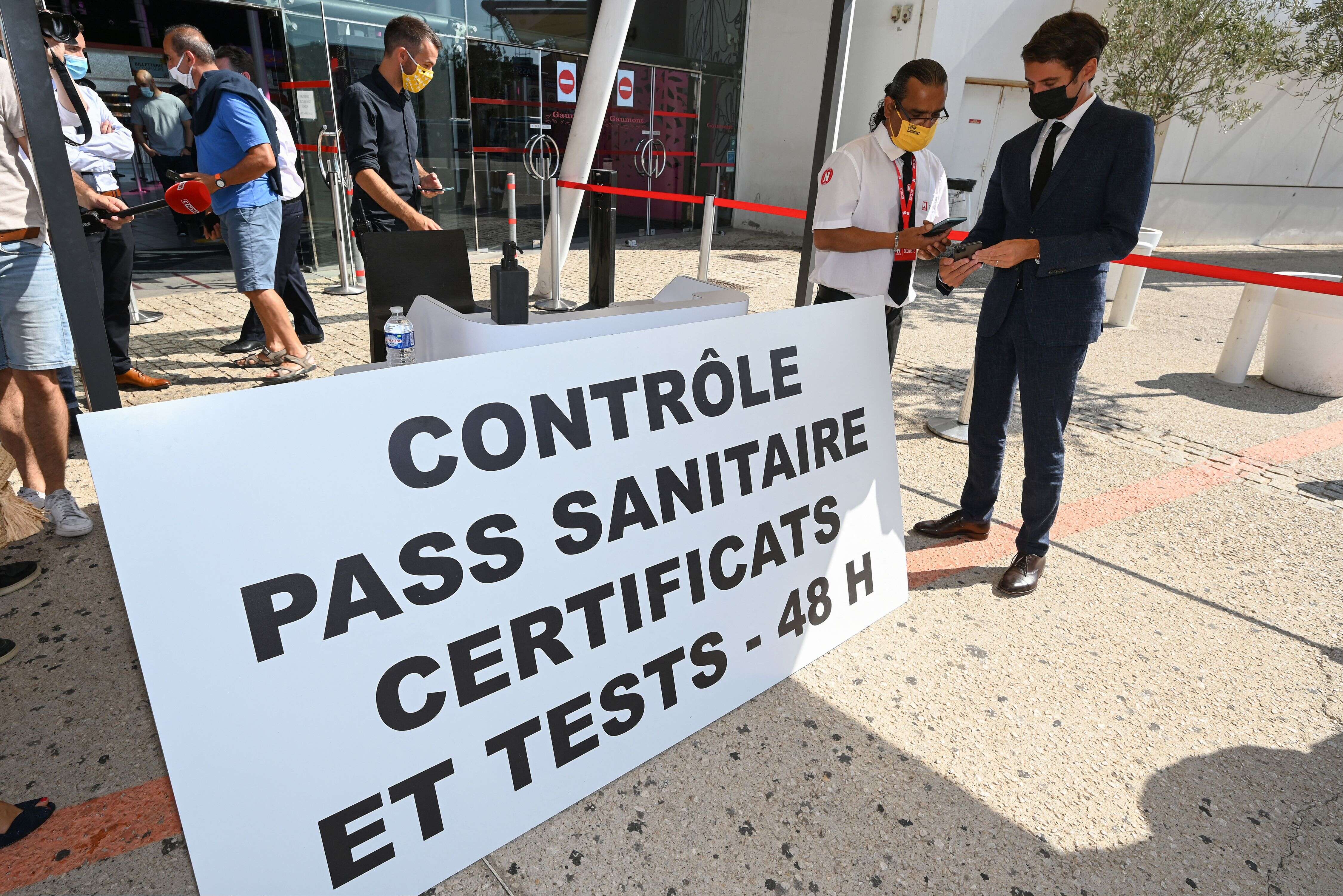 Le porte-parole du gouvernement Gabriel Attal montrant son pass sanitaire lors d'une visite d'un cinéma à Montpellier, le 29 juillet 2021.