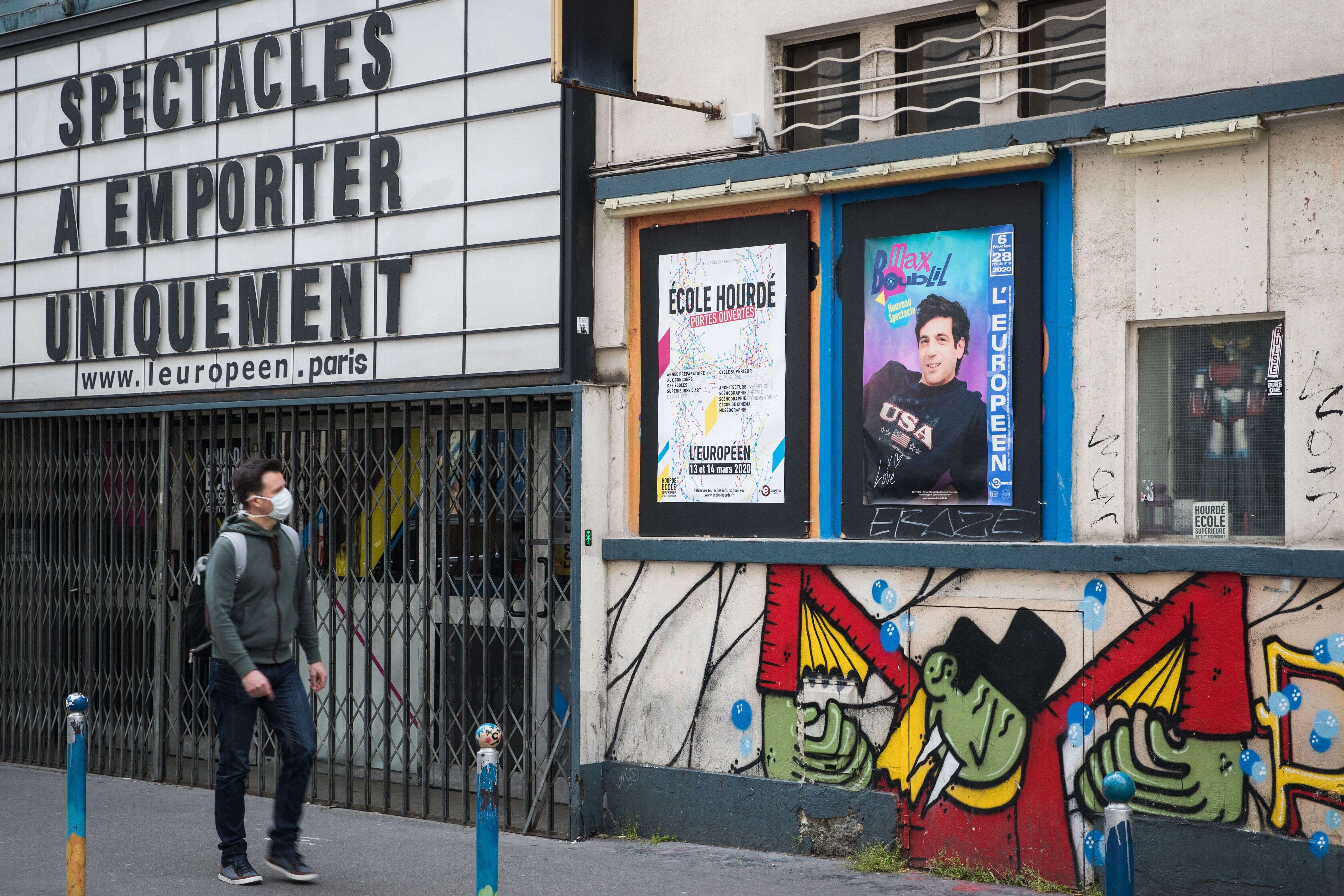 Pendant le confinement, un homme passe devant la salle de spectacles L'Européen à Paris, qui précise sur sa façade: 