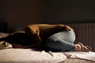 Une femme, en boule, dort sur son lit (photo d'illustration).
