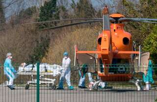 À l'hôpital Emile Muller de Mulhouse, surchargé par les cas de coronavirus, des soignants emmènent un patient vers un hélicoptère médical pour l'évacuer vers un autre hôpital, le 19 mars 2020.