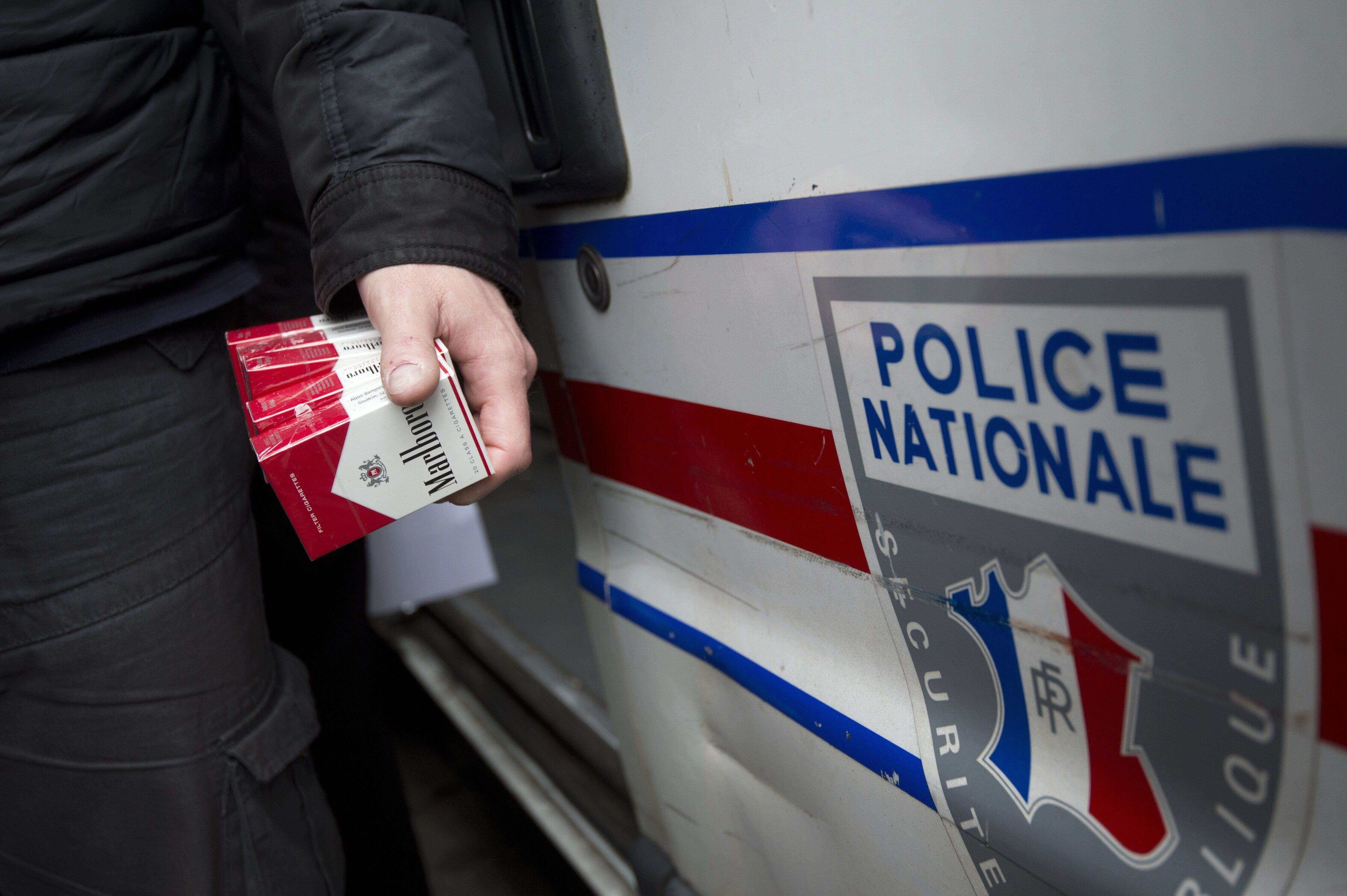Un policier français tenant des paquets de cigarettes achetés en contrebande à des vendeurs à la sauvette à Aubervilliers, au Nord de Paris.