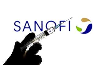 SPAIN - 2021/07/13: In this photo illustration a hand holding a medical syringe seen in front of the Sanofi logo. (Photo Illustration by Thiago Prudencio/SOPA Images/LightRocket via Getty Images)