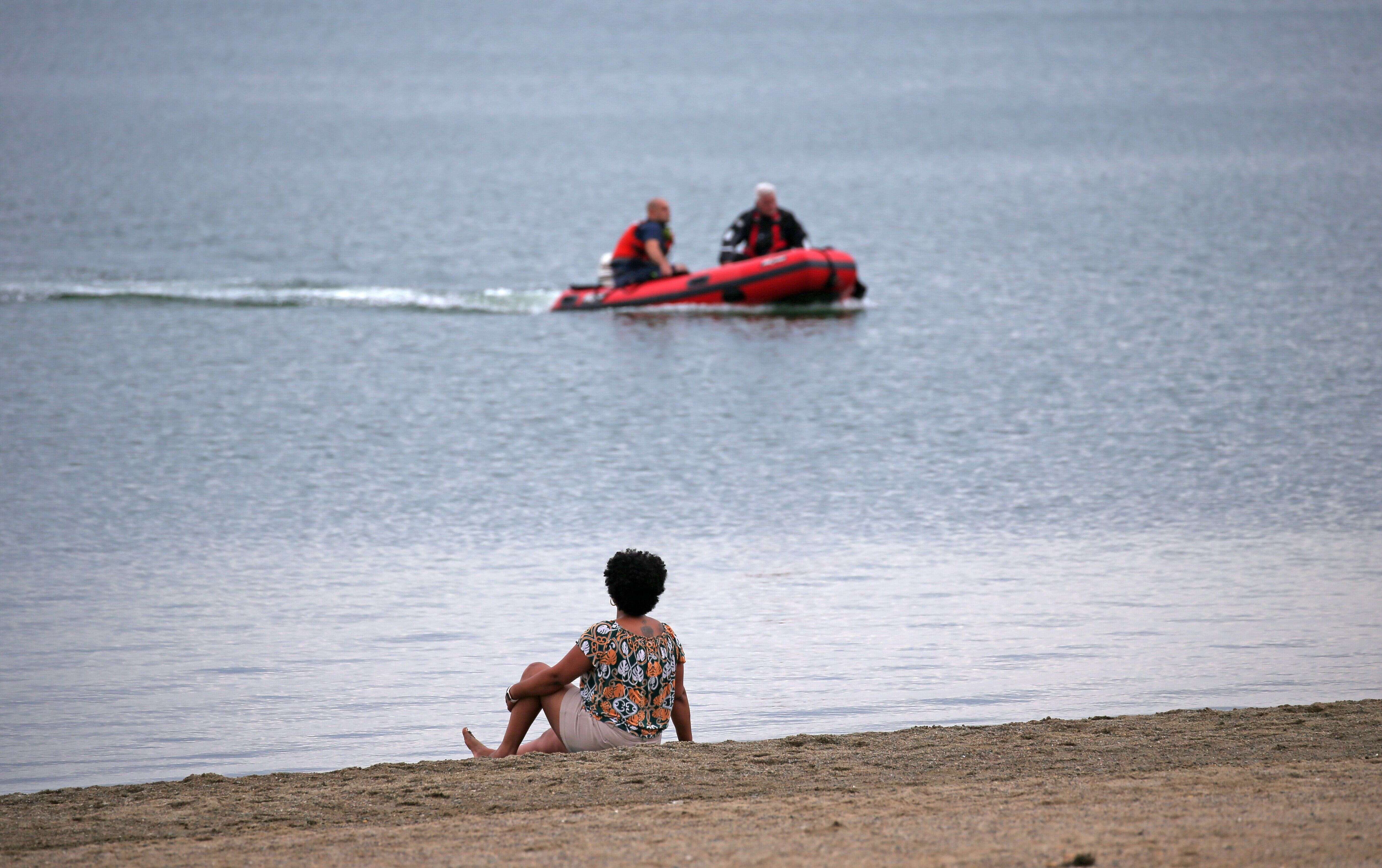 Après un début d'été inquiétant, le nombre de noyades recule comparé à 2018 (Photo prétexte d'une femme assise sur une plage regardant un bateau de secours à Boston en juillet 2021 par David L. Ryan/The Boston Globe via Getty Images)