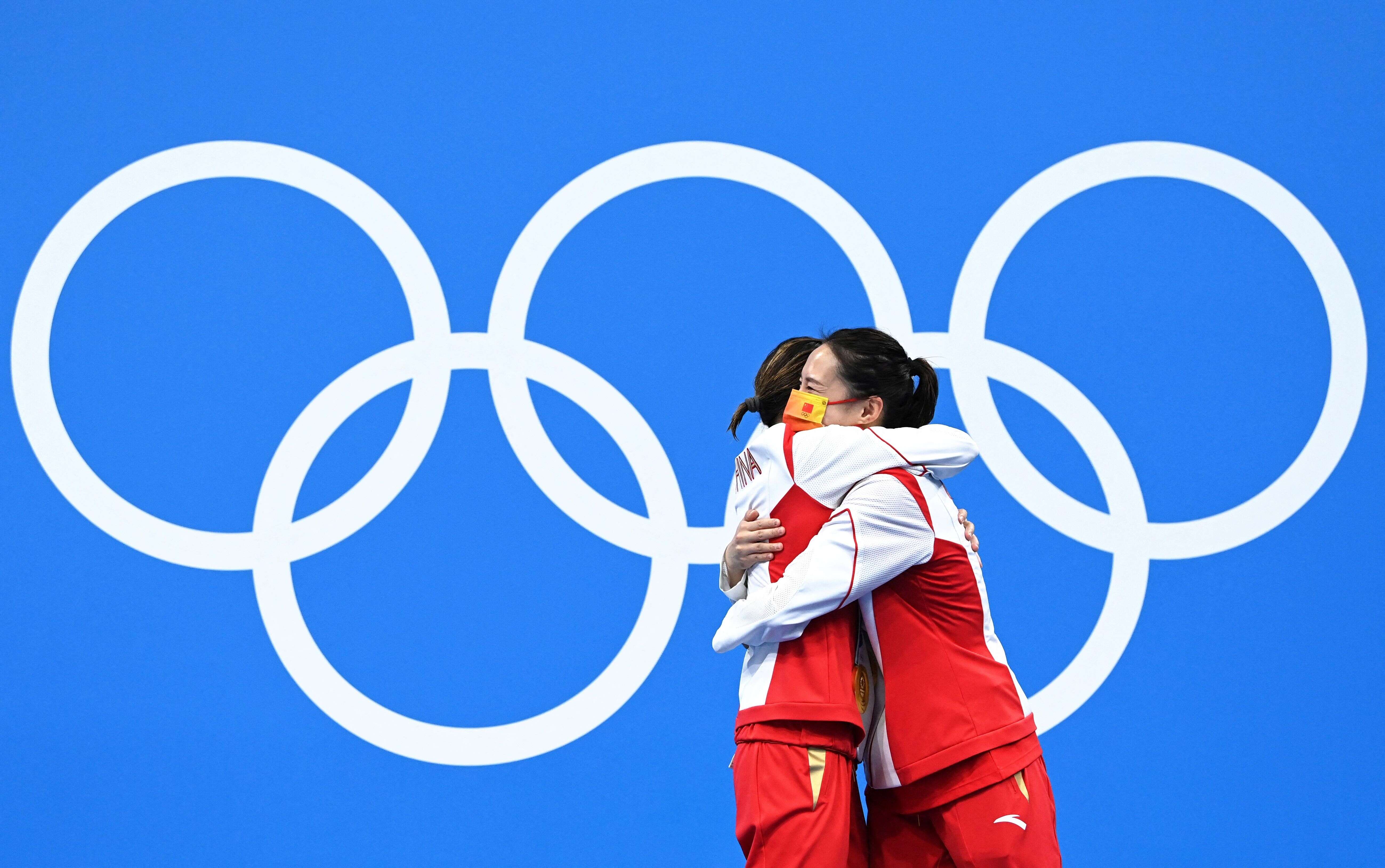 Les Chinoises Shi Tingmao et Wang Han se serrent dans les bras sur le podium après leur titre olympique en plongeon - tremplin à 3m synchronisé, le 25 juillet 2021.
