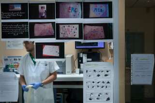 Un médecin travaille derrière une vitre sur laquelle sont affichés des dessins d'enfants en soutien aux soignants pendant la pandémie de COVID-19 aux urgences de l'hôpital Delafontaine à Saint-Denis, le 17 juillet 2020. (Photo JOEL SAGET/AFP via Getty Images)