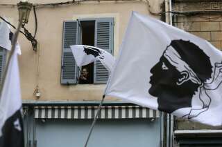Une femme agite depuis sa fenêtre un drapeau corse le 13 mars 2022, lors d'un rassemblement de soutien à la figure nationaliste corse Yvan Colonna une semaine après son agression en prison à Arles.