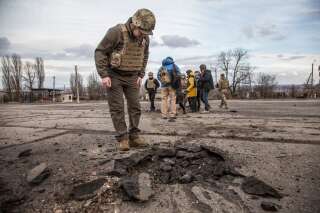 Un soldat ukrainien devant l'impact d'un obus dans le village de Novoluhanske, près de Louhansk dans le Donbass, le 19 février 2022.