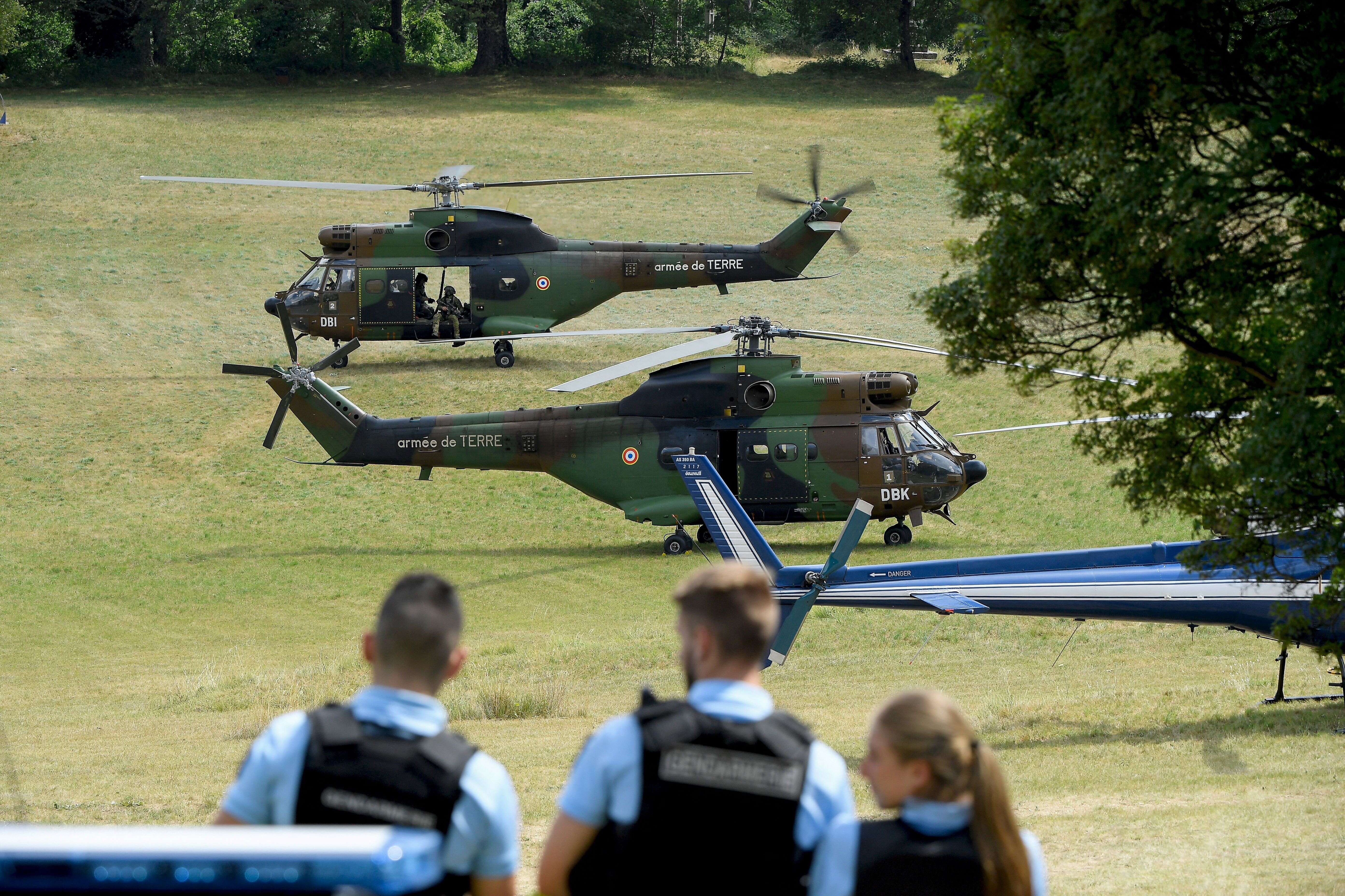 Des gendarmes devant des hélicoptères de l'armée de terre dans un champ de Gréolières, dans le Var, pour retrouver le suspect d'un meurtre le 19 juillet 2021.