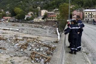 Des riverains et des pompiers le 3 octobre sur un pont de Roquebillière regardant les dégâts provoqués par les intempéries et les inondations (Photo by NICOLAS TUCAT / AFP)
