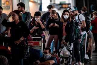 Des passagers portent des masques pour prévenir la propagation du coronavirus, COVID-19, alors qu'ils attendent à l'aéroport international de Santiago du Chili, le 18 mars 2020.