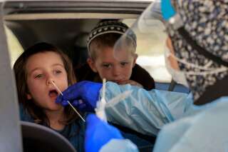 Le pass sanitaire en Israël imposé dès 3 ans face à la montée du variant Delta (Photo d'enfants se faisant tester dans une voiture à Jérusalem contre le Covid-19 par MENAHEM KAHANA / AFP)