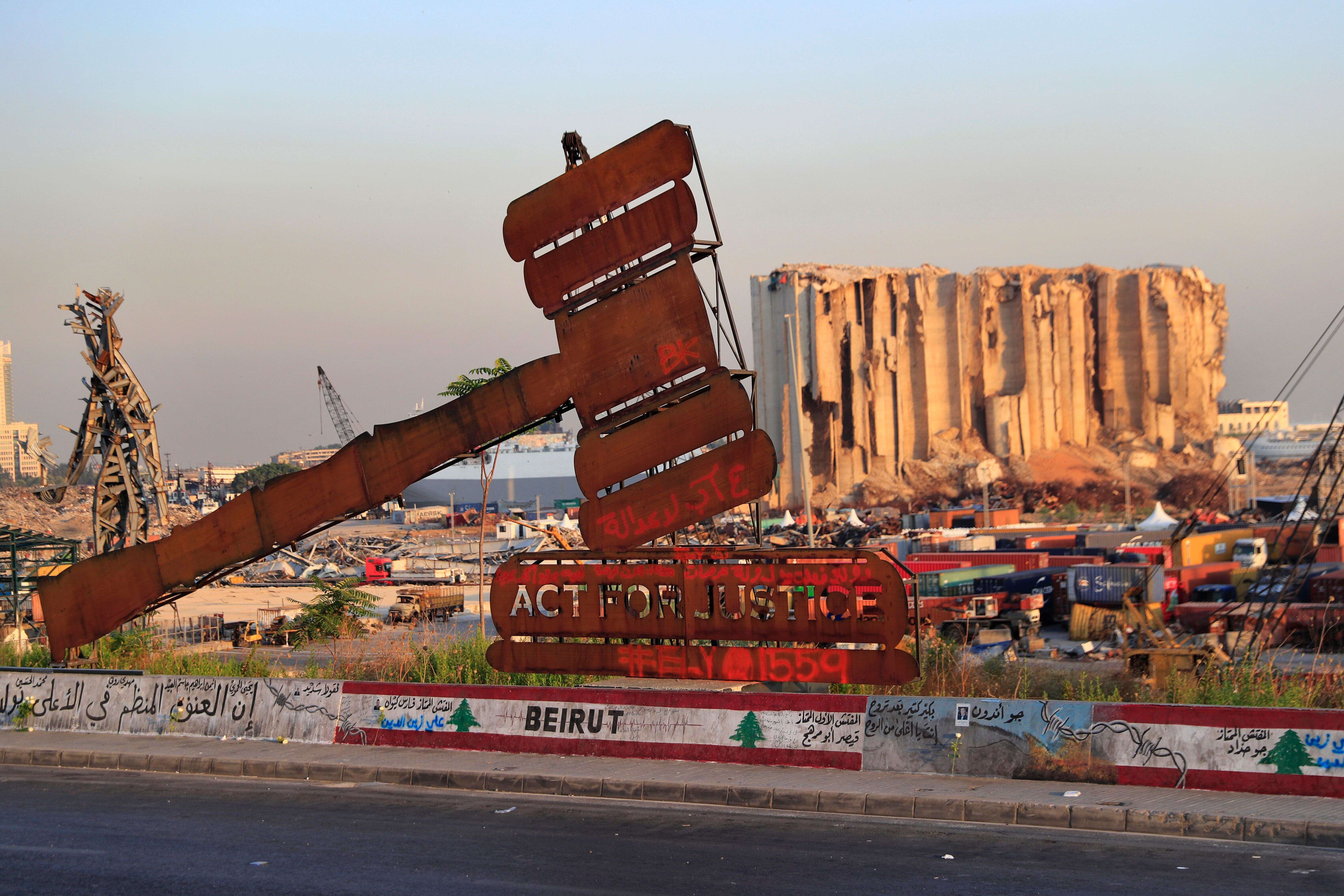 Photo prise le 4 août devant les ruines du port de Beyrouth. Le marteau est synonyme de justice, que les Libanais attendent toujours face aux lenteurs de l'enquête.(AP Photo/Hussein Malla, File)