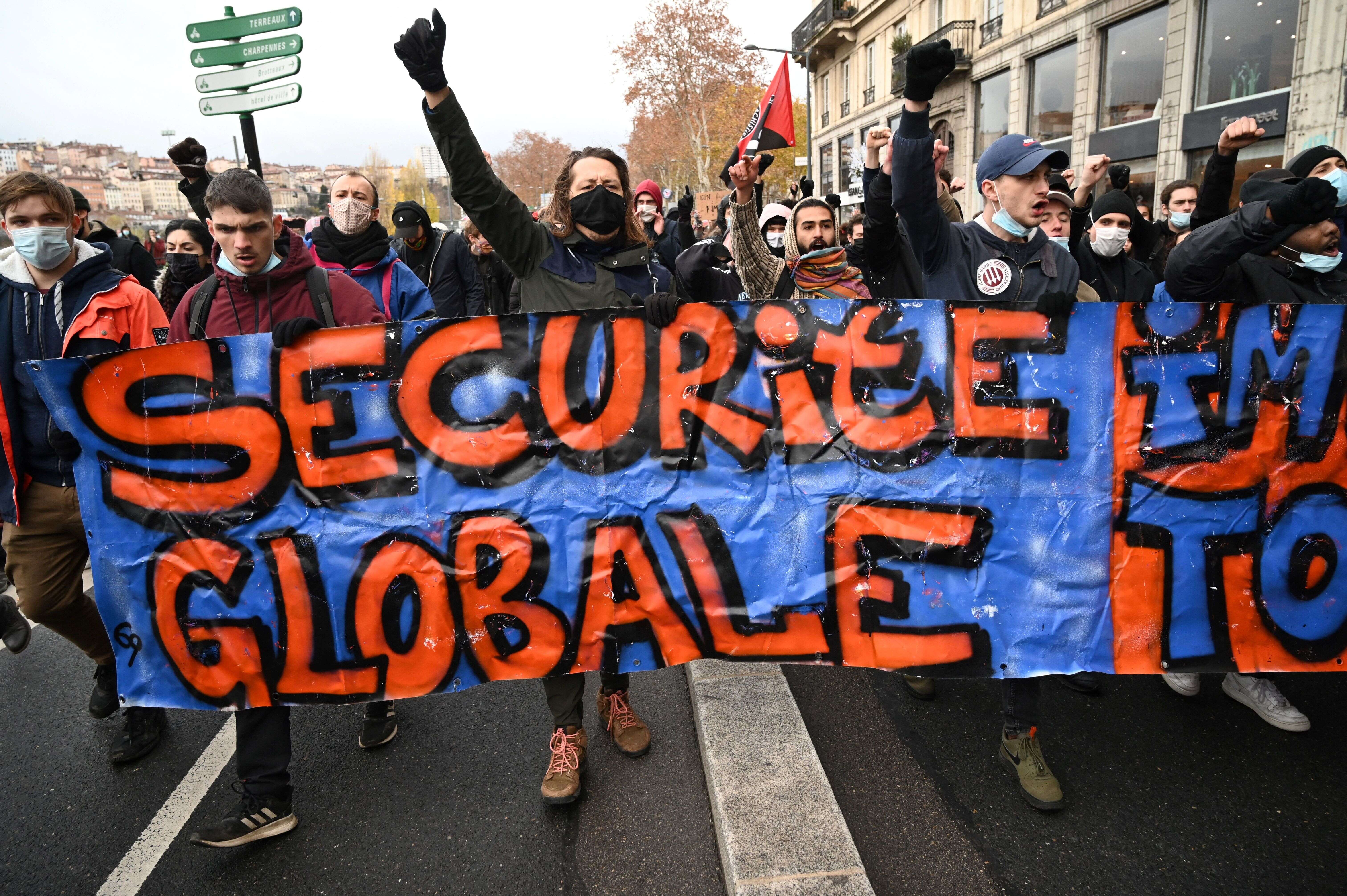 Des manifestants brandissent une banderole et lèvent leur poing en opposition à la loi Sécurité globale, en décembre 2020.