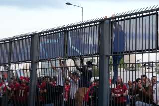 Des supporters grimpent sur la clôture devant le Stade de France avant le match de football de la finale de la Ligue des champions entre Liverpool et le Real Madrid, à Saint-Denis près de Paris, le samedi 28 mai 2022.