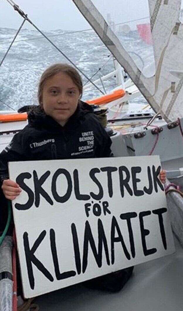 Greta Thunberg à bord du Malizia II avec un panneau affichant 