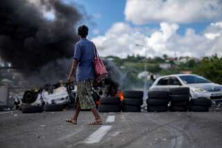 En Martinique, 150 enquêtes ouvertes après des pillages (Photo d'illustration d'une femme marchand devant une barricade enflammée près de l'aéroport de Fort de France le 24 novembre. Par REUTERS/Ricardo Arduengo)