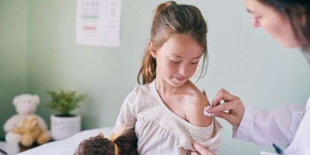 Shot of a pediatrician cleaning her young patients arm with a cotton ball