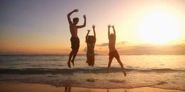 Caucasian children jumping for joy on beach