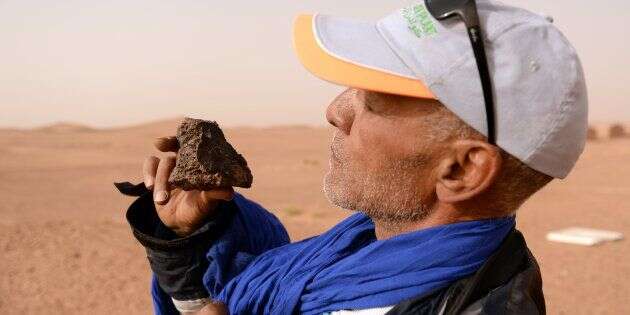 Un chasseur de météorite examine un rocher dans le sud du Maroc, le 25 mars 2018.