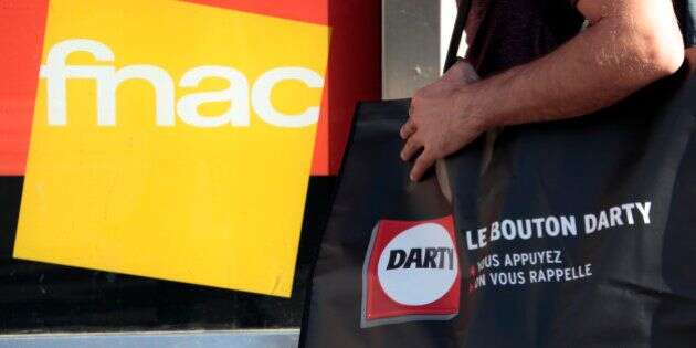 A picture illustration shows a man holding a bag of electrical goods retailer Darty as he stands near a store window with a logo of French music retailer Fnac in Nice, France, November 6, 2015. Books and music retailer Fnac said on Friday that it had raised its offer for electrical goods company Darty in an agreed deal that would create a French market leader in white goods. The companies said in a statement that the new offer of about 116 pence per Darty share, up from 101 pence, valued Darty at about 615 million pounds ($934 million), against 533 million previously.   REUTERS/Eric Gaillard