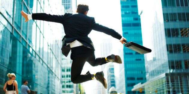 Businessman jumping for joy on city street.