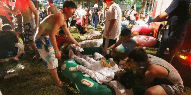 Emergency rescue workers and concert spectators tend to injured victims from an explosion during a music concert at the Formosa Water Park in New Taipei City, Taiwan, Saturday, June 27, 2015. The New Taipei City fire department says 200 people were injured in an accidental explosion of colored theatrical powder Saturday night near a performance stage where about 1,000 people were gathered for party. (AP Photo)    TAIWAN OUT