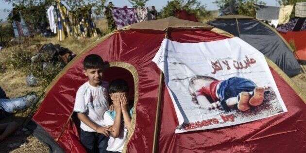 Children sit inside a tent bearing an image of  three-year-old Aylan Kurdi, the Syrian toddler who's body washed up on a beach in Turkey,  as Syrian migrants gather near the highway on the way to the Turkish-Bulgarian border at Edirne on September 15, 2015, in Edirne.  Over half a million migrants have crossed the European Union's border so far this year, up from 280,000 in 2014, the bloc's Frontex border agency said -- but warned some people may have been counted twice.  AFP PHOTO/BULENT KILIC        (Photo credit should read BULENT KILIC/AFP/Getty Images)
