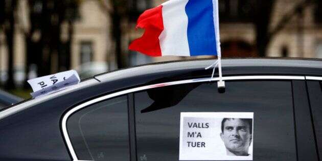 A French flag flies from a car during a demonstration by LOTI transport drivers (public transport on demand) and VTC drivers, including Uber France, to denounce the measures in favor to French taxis drivers in Paris, France, February 3, 2016. The placard