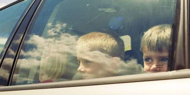 Two boys (4-9) in car, looking through window