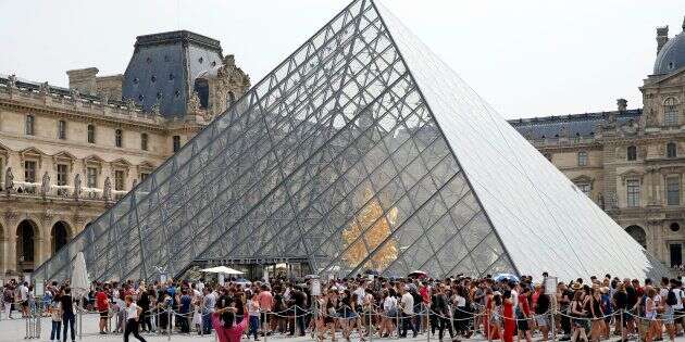 Des touristes font la queue devant la pyramide du Louvre en juillet 2018.